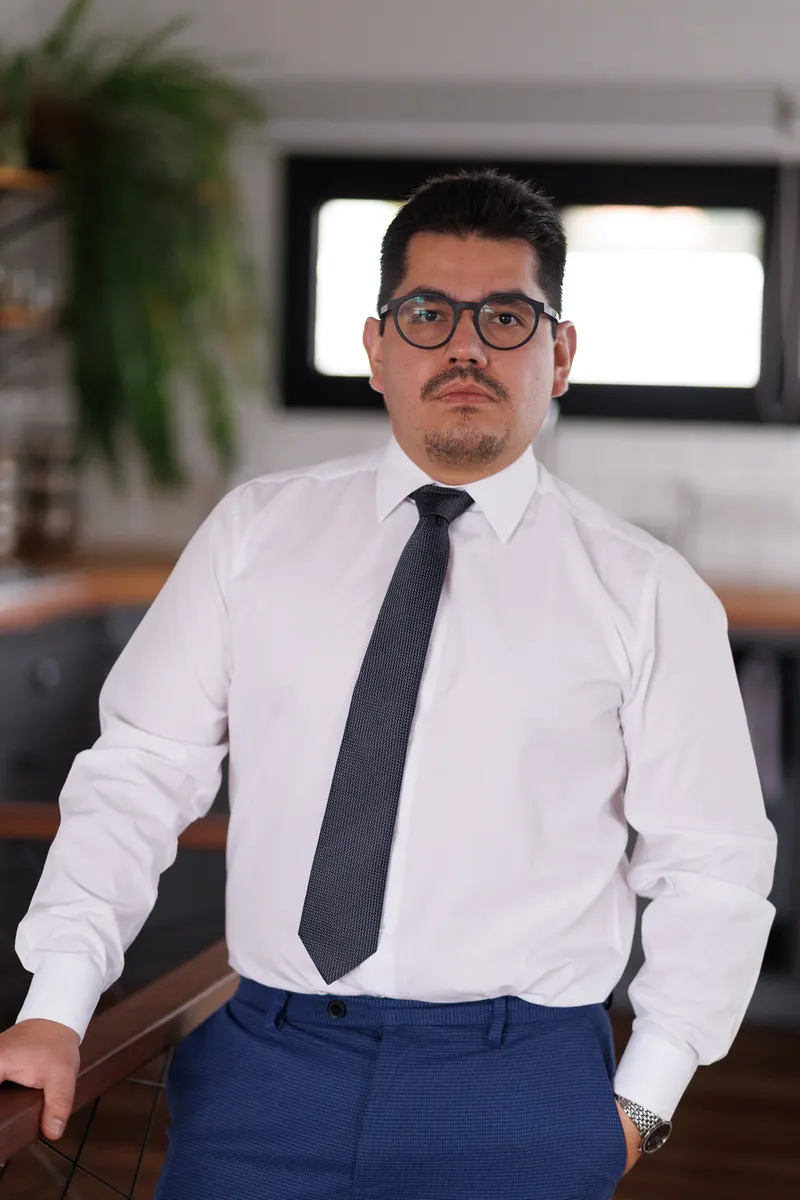 Dr. John Terrazas de pé, de camisa branca e gravata