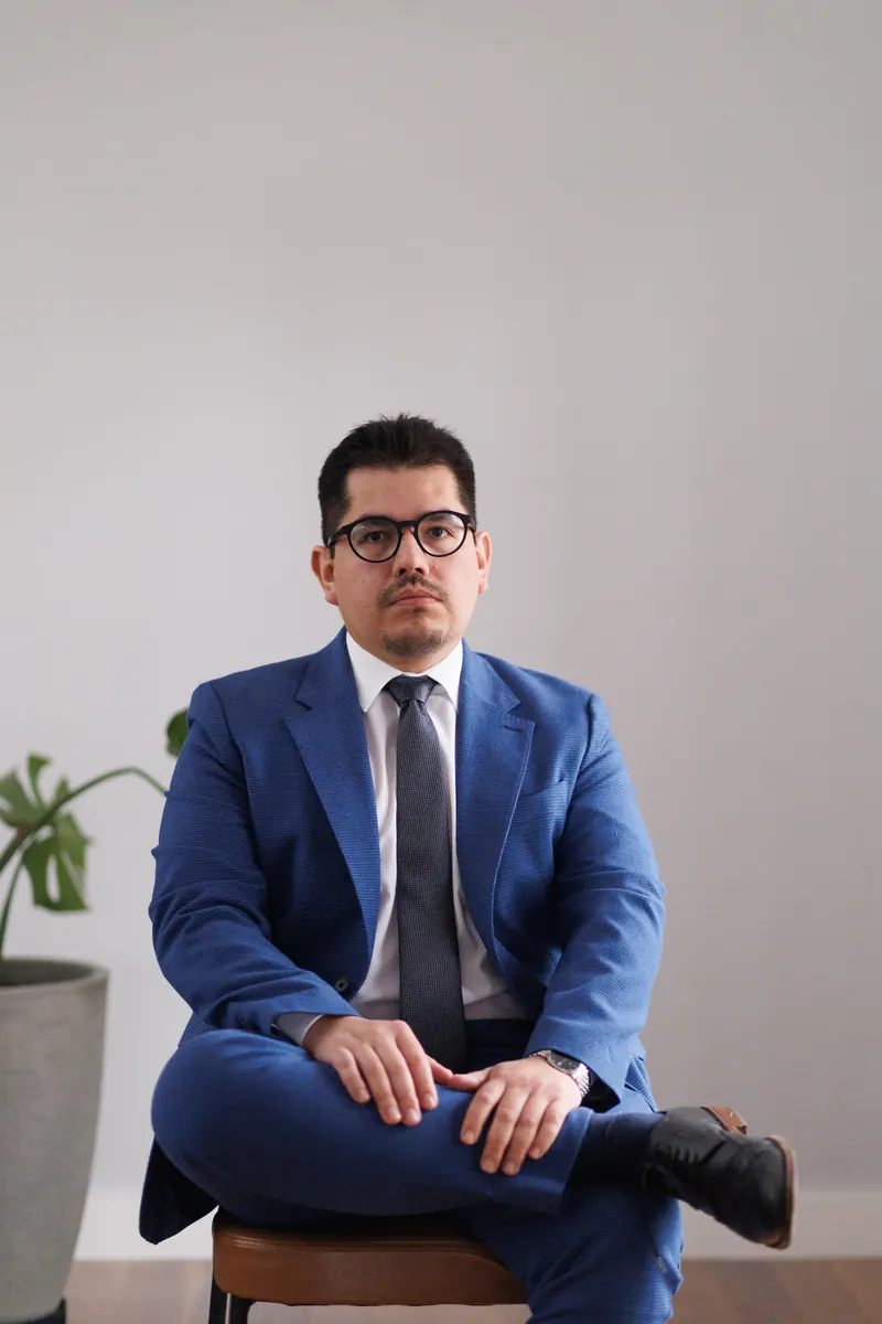 Dr. John Terrazas sentado, de terno azul, em um ambiente claro