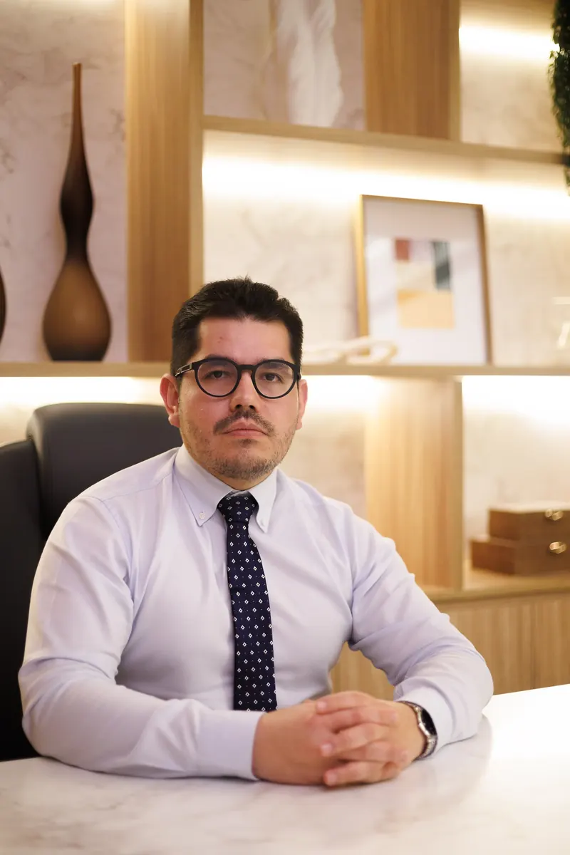 Dr. John Terrazas sentado à mesa do consultório