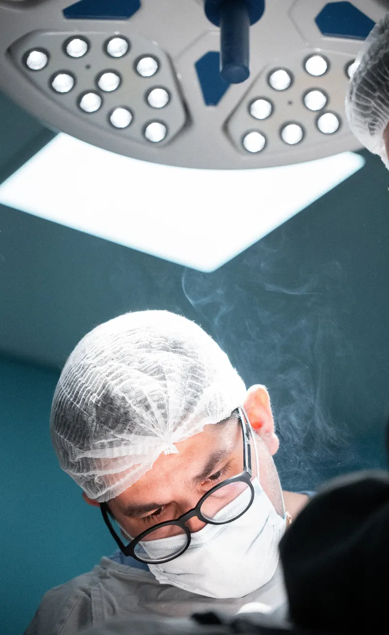Dr. John Terrazas operando sob a luz do foco cirúrgico